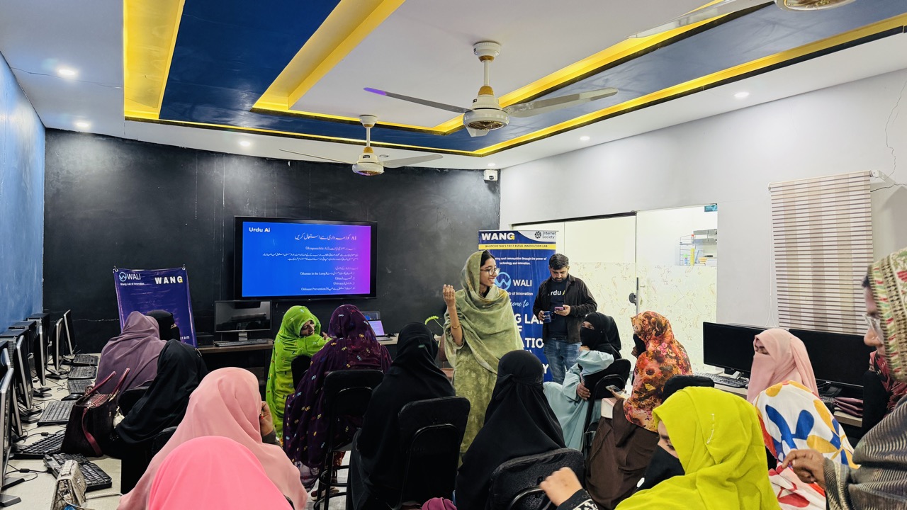 Women at Urdu AI digital training session in WALI lab with WANG and WALI banners